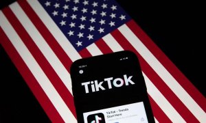 Un móvil con la aplicación China TikTok, sobre una bandera de EEUU.