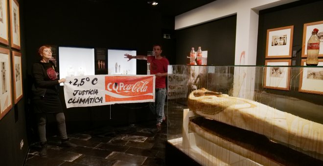 Dos activistas bañan con un líquido que simula petróleo una vitrina del Museo Egipcio de Barcelona