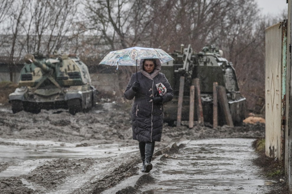 Una mujer camina frente a vehículos blindados rusos en la estación de tren de la región de Rostov, Rusia, este 24 de febrero. Las tropas rusas lanzaron una importante operación militar en Ucrania tras semanas de intensa diplomacia y la imposición de sanci