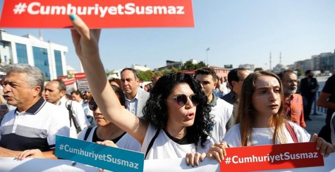 Varias presonas muestran el lema 'Cumhuriyet no se silencia' durante una concentración delante del Palacio de Justicia de Estambul (Turquía) hoy, 24 de julio de 2017. Empleados del diario se sientan en el banquillo de los acusados hoy acusados de colabora