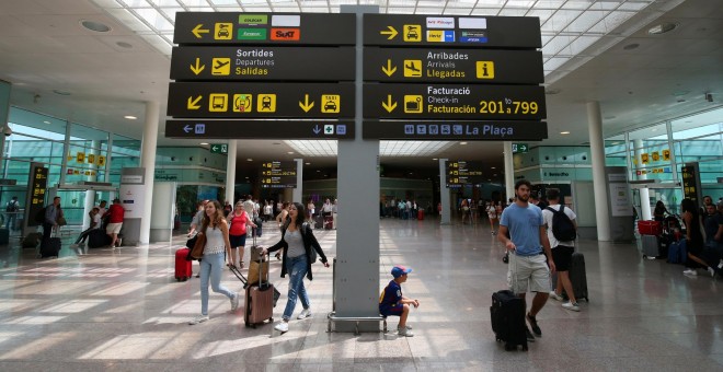 Viajeros junto a uno de los paneles informativos del Aeropuerto Barcelona-El Prat. REUTERS/Albert Gea