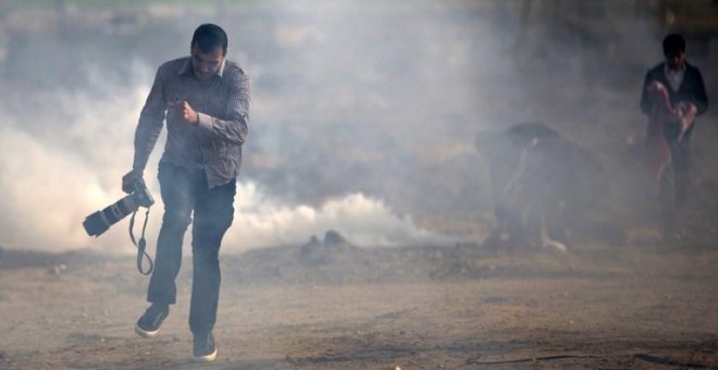 Un fotógrafo palestino trata de evitar el gas lacrimógeno lanzado por las fuerzas israelís. MOHAMMED ABED/AFP/Archivo