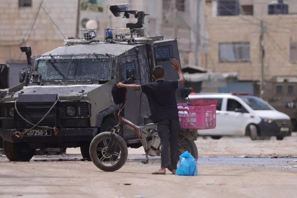 Tropas israelíes frente a un joven ciclista durante una operación militar en la ciudad cisjordana de Yenín, el 28 de agosto de 2024. — Alaa Badarneh / EFE