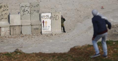 Un soldado israelí graba a un joven palestino. REUTERS