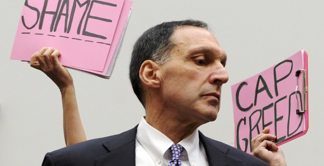 Algunos manifestantes sostienen pancartas detrás del presidente ejecutivo de Lehman Brothers, Richard Fuld, antes de iniciar su comparecencia en el Congreso de EEUU para explicar la quiebra de la entidad, y en la que aseguró que las autoridades estadounid