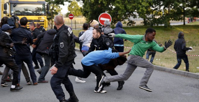 Varios migrantes escapan de las autoridades francesas antes de intentar tomar un tren en su ruta hacia Inglaterra, en Calais (Francia). EFE