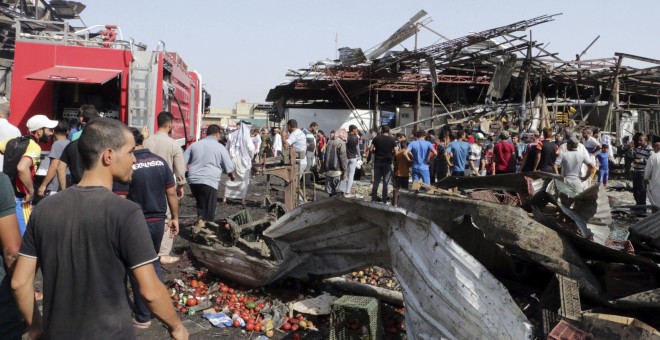 Varias personas caminan por el lugar donde se ha producido un atentado en un mercado en Bagdad (Irak) reivindicado por el Estado Islámico. EFE/Ahmed Ali