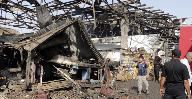 Varias personas caminan por el lugar donde se ha producido un atentado en un mercado en Bagdad (Irak) reivindicado por el grupo terrorista Estado Islámico. EFE/Ahmed Ali