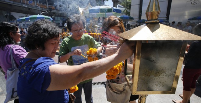 Turistas malasios queman incienso ante el altar del templo de Erawan donde el pasado lunes estalló una bomba en Bangkok.- EFE