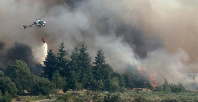 Un helicóptero intenta sofocar el incendio de Muiños, en Ourense, donde se ha decretado la situación 2 por la proximidad a las viviendas/EFE