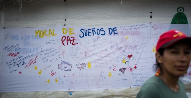 Una guerrillera de las FARC pasa delante de un mural en favor de los acuerdos de paz con el Gobierno colombiano, en la zona veredal de transición de La Elvira, en el Cauca.- JAIRO VARGAS