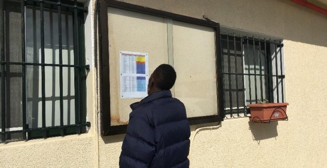 Un migrante residente en el CETI de Ceuta ojea la lista de personas que serán trasladadas a la península.- HRW