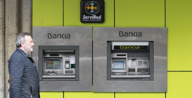 Un hombre pasa frente a los cajeros automáticos de una sucursal de Bankia. E.P.