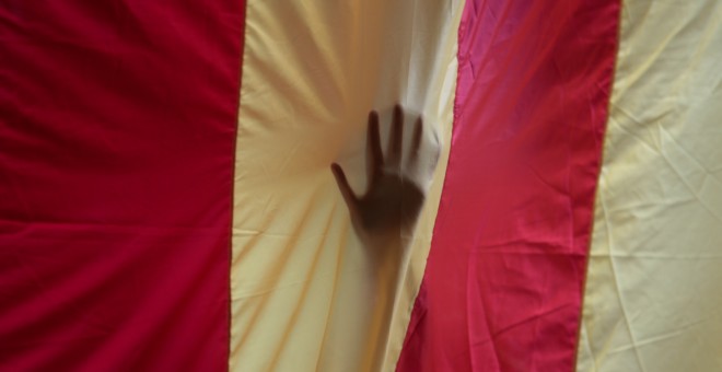 Una mano vista a través de una estelada gigante colocada en el edificio histórico de la Universidad de Barcelona. REUTERS/Enrique Calvo