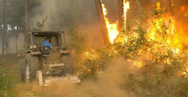 Un hombre subido en un tractor se sitúa frente al fuego del incendio de Zamanes, Vigo. EFE/Salvador Sas