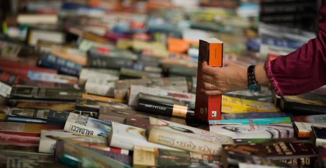 Un hombre compra un libro en un puesto de libros de las Ramblas de Barcelona durante la diada de Sant Jordi. (ENRIC FONTCUBERTA | EFE)