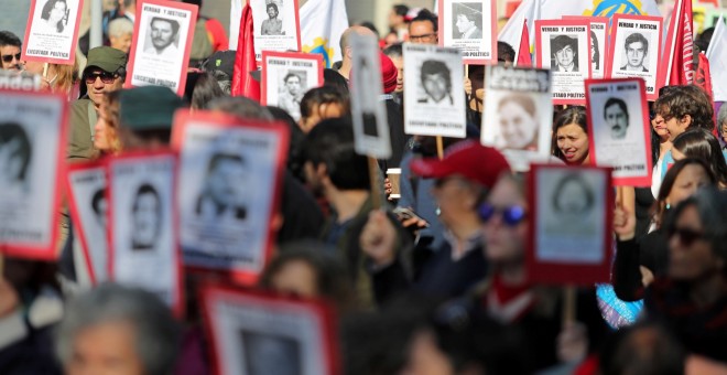 Activistas por los derechos humanos con pancartas con imágenes sobre los desaparecidos durante la dictadura de Pinochet - Reuters