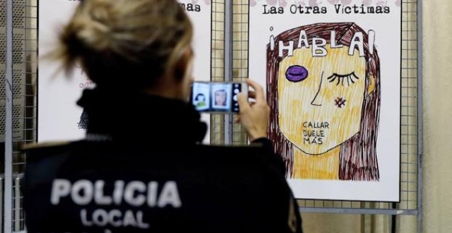 Una agente de la Policía Local fotografía un cartel contra la violencia machista. / EFE