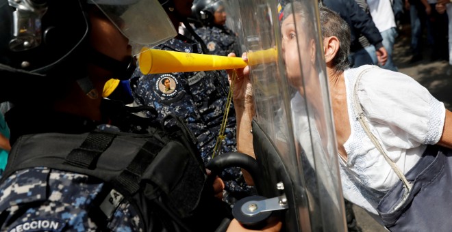 Una manifestante increpa a un miembro de la Guardia Nacional Bolivariana que le impide el paso durante una movilización contra el Gobierno de maduro.- REUTERS/Carlos Garcia Rawlins