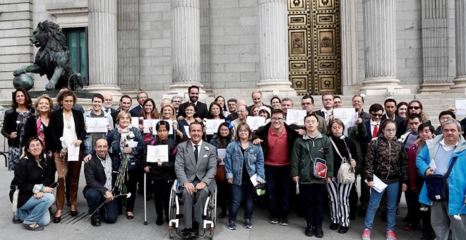 Varios diputados posan junto a miembros de diferentes colectivos a las puertas del Congreso de los Diputados, donde se ha debatido la reforma de la Ley Orgánica de Régimen Electoral General (Loreg) que otorgará el derecho de sufragio a todas las personas