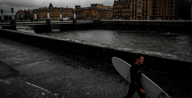 27/05/2019 - Un surfista camina junto al río Urumea este lunes en San Sebastián, donde las precipitaciones no han cesado en todo el día y se prevé que la situación no cambie hasta el jueves | EFE/ Javier Etxezarreta