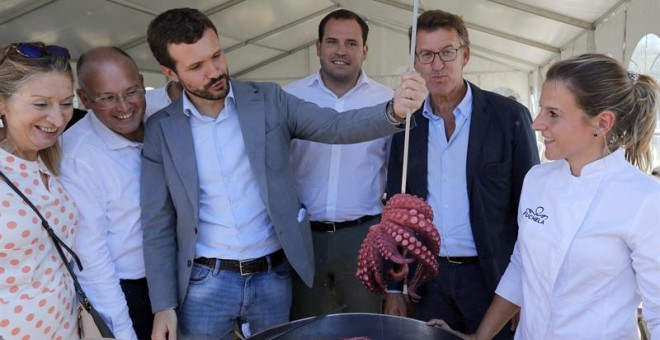 El presidente del Partido Popular, Pablo Casado, sacando un pulpo y el presidente de la Xunta de Galicia, Alberto Núñez Feijóo, acompañados por cargos del partido en la localidad de Cerdedo-Cotobade. /EFE