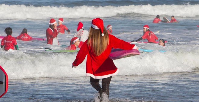 Un año más los Papá Noeles surferos se han dado cita en la playa de Patos en Nigrán para cabalgar las olas en un día primaveral, que hacía tiempo que no se veía en Galicia . EFE / Salvador Sas