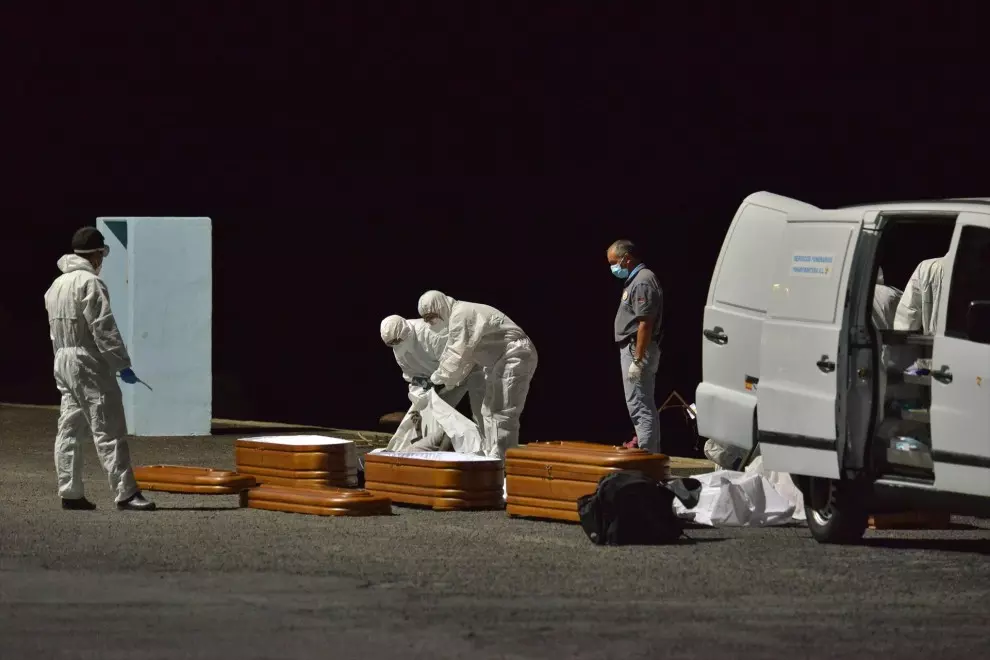 Varios trabajadores introducen en un ataúd a una persona fallecida en alta mar tras intentar llegar a la costa a bordo de una patera, a 11 de abril de 2021, en el puerto de la Restinga, Canarias.