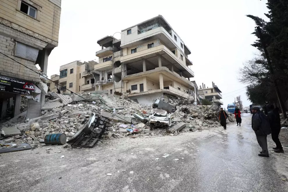 Gente camina al lado de varios edificios derrumbados por el terremoto en la ciudad de Armanaz, en el distrito de Idlib (Siria) este 6 de febrero de 2023.