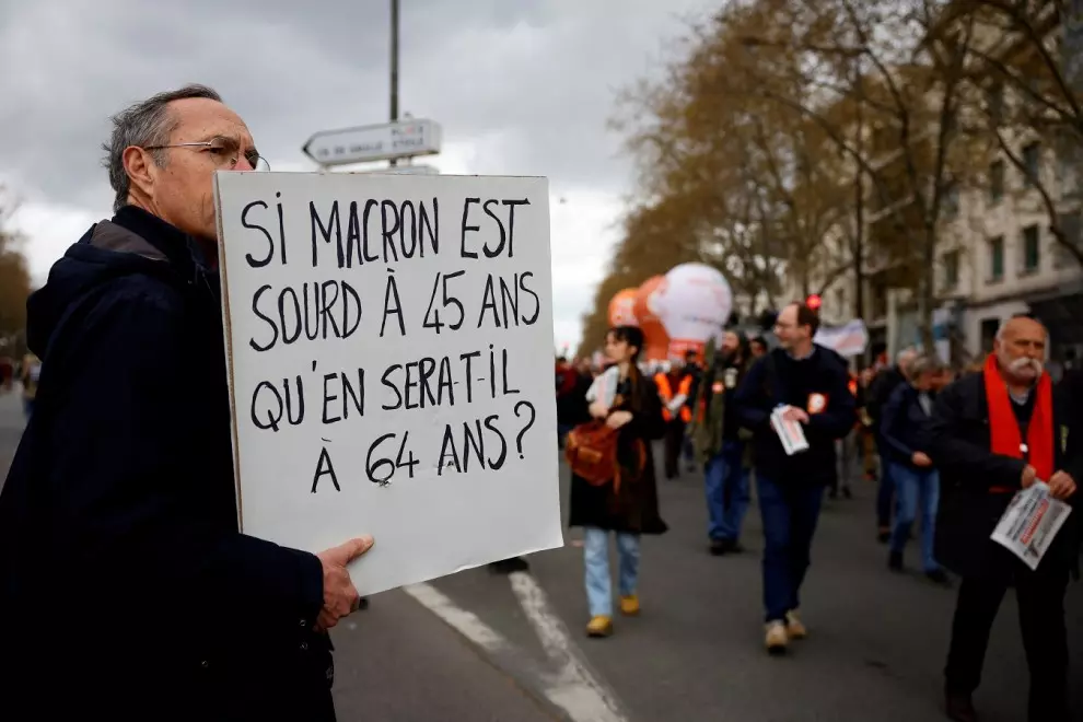 Un manifestante sostiene una pancarta contra la elevación de la edad de jubilación a los 64 años ('Sí Macron está sordo a los 45 años, ¿cómo estará a los 64?', dice), en París, en la nueva jornada de protestas, la úndécima, contra el proyecto del presiden