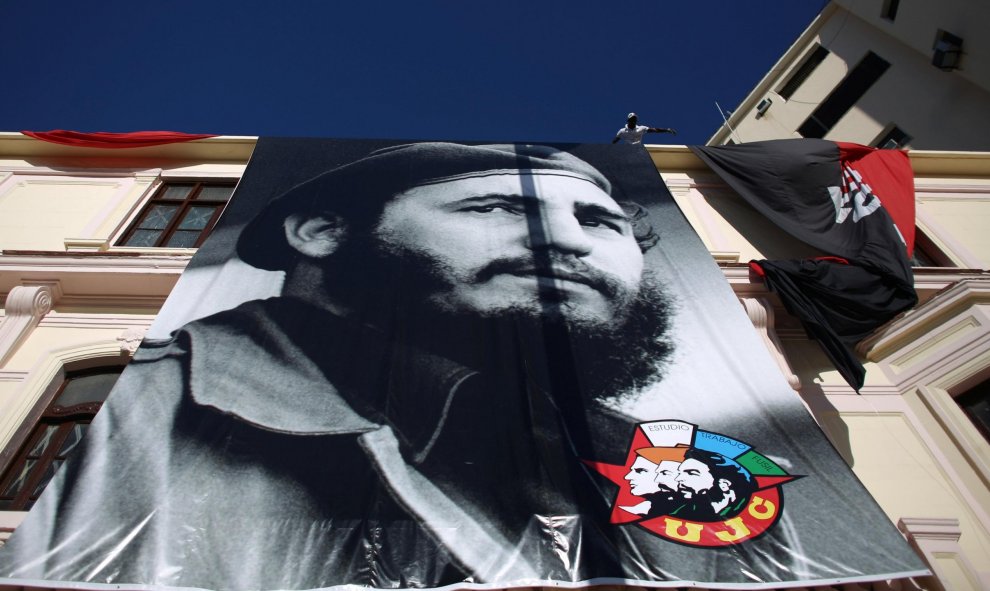 Un hombre despliega en la fachade de un edificio de La Habana un enorme retraro de Fidel Castro, para celebrar su 90 cumpleaños. REUTERS/Alexandre Meneghini