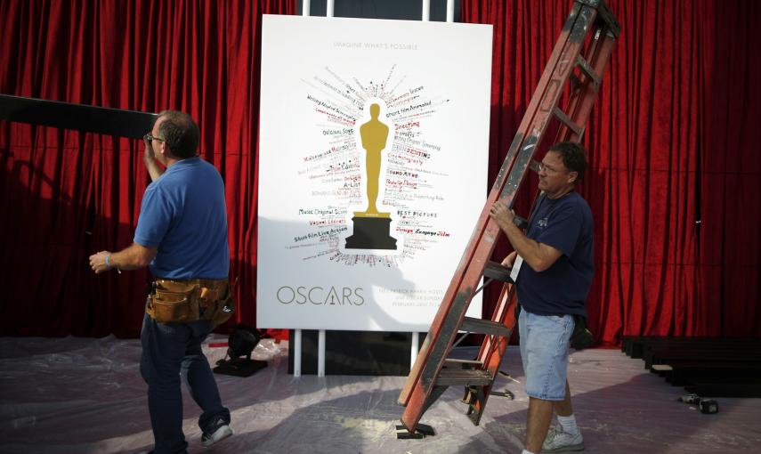 Unos trabajadores pasan junto al poster que anuncia la ceremonia de entrega de los 87ª premios Oscar, en el Dolby Theater de Los Angeles. REUTERS/Lucy Nicholson