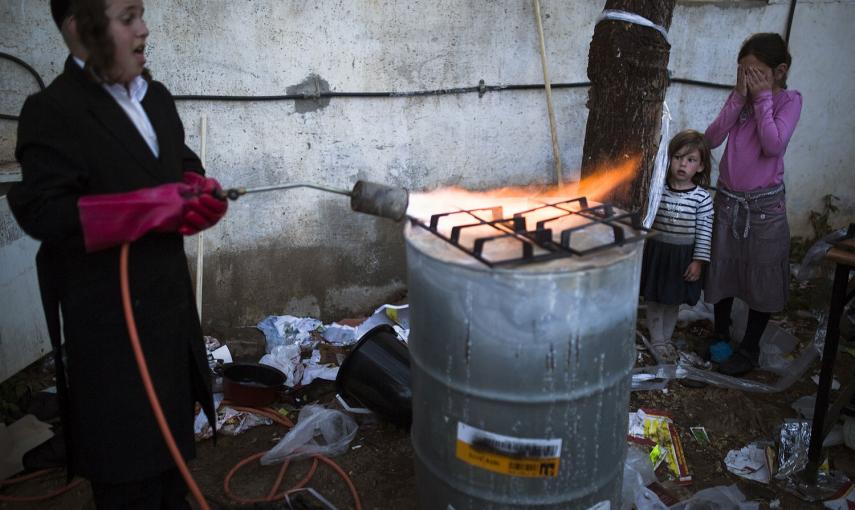 Un judío ultraortodoxo calienta los hierros de una cocina para eliminar restos de levadura, durante la preparación de la Pascua en la ciudad de Ashdod. /AMIR COHEN (REUTERS)