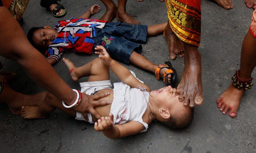 Un hombre santo hindú toca a un niño con su pie durante un ritual para bendecirlo, durante una procesión religiosa para conmemorar la festividad de Gajan en Calcuta.- RUPAK DE CHOWDHURI (REUTERS)