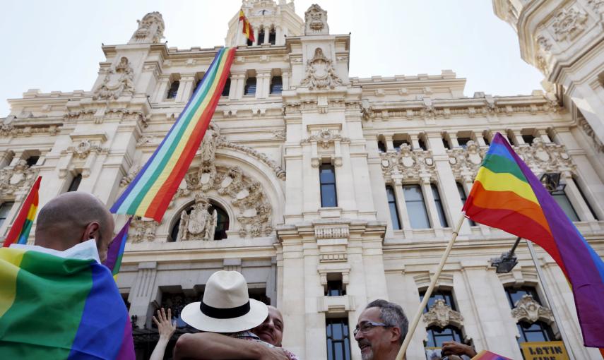 Una bandera con los colores del arco iris, símbolo LGTB, ondea en el Ayuntamiento de Madrid mientras algunas parejas homosexuales lo celebran en los aledaños del consistorio. REUTERS