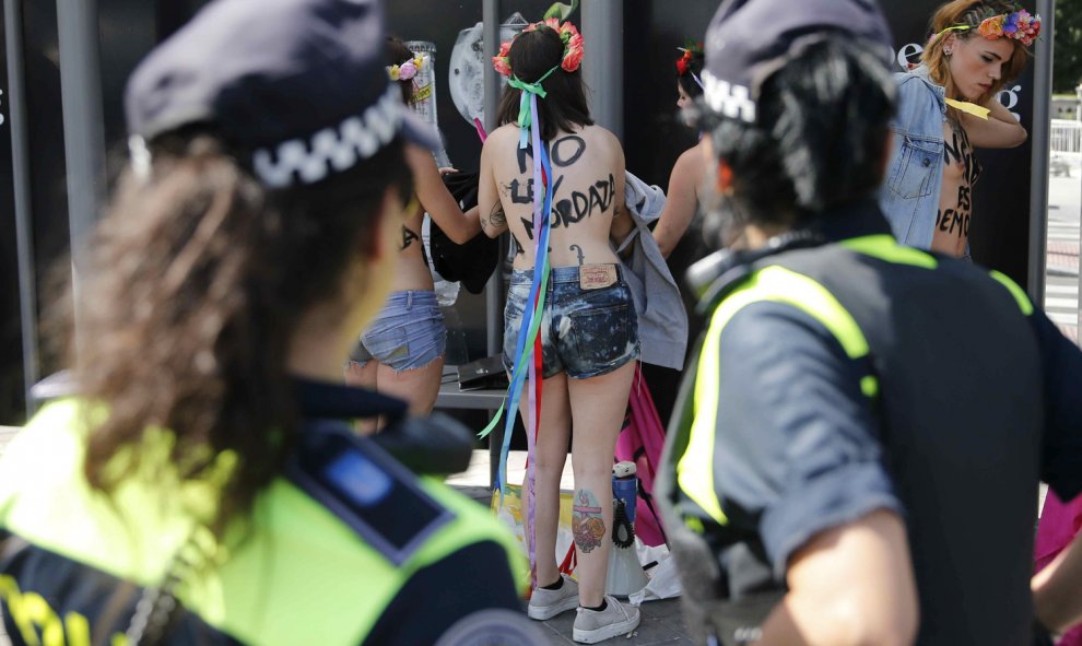 Dos policías municipales observan a las activistas de Femen que se han encaramado hoy en una acción sorpresa a la fuente de Cibeles para protestar contra la ley mordaza.- EFE/Juan Carlos Hidalgo