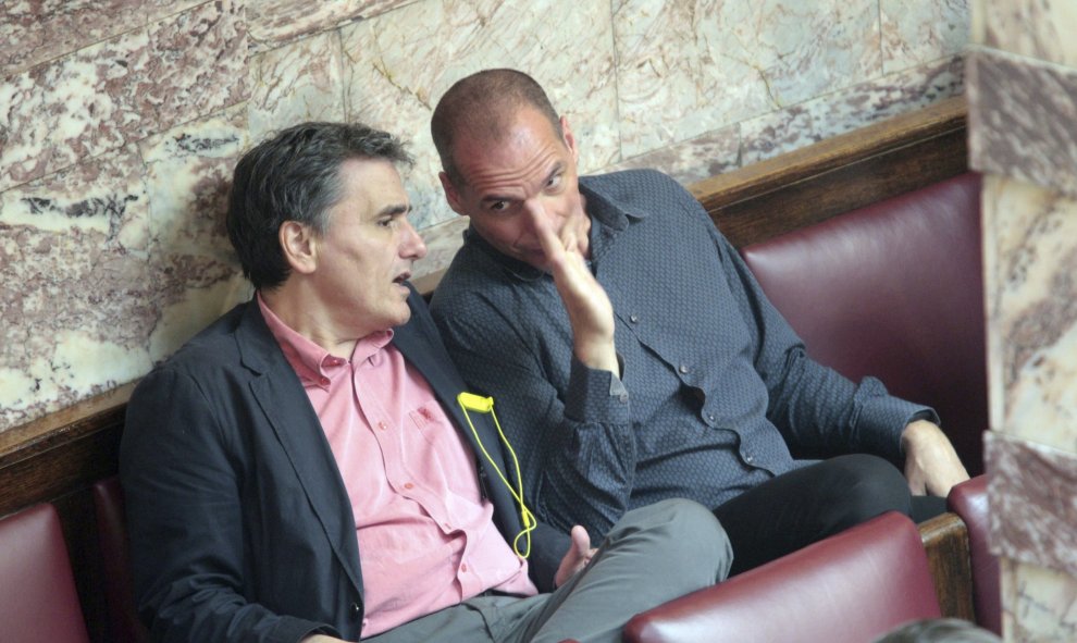 El ministro de Finanzas, Euclides Tsakalotos (i) conserva con su predecesor en el cargo Yanis Varoufakis (d) durante una sesión en el Parlamento en Atenas, Grecia hoy 9 de julio de 2015. El portavoz del Gobierno griego, Gavriil Sakelaridis, confía en que