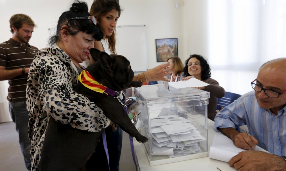 Una mujer carga con su perrro (que lleva en el collar los colores de la bandera catalana) frente a la urna de su colegio electoral en  Barcelona. REUTERS/ Gustau Nacarino