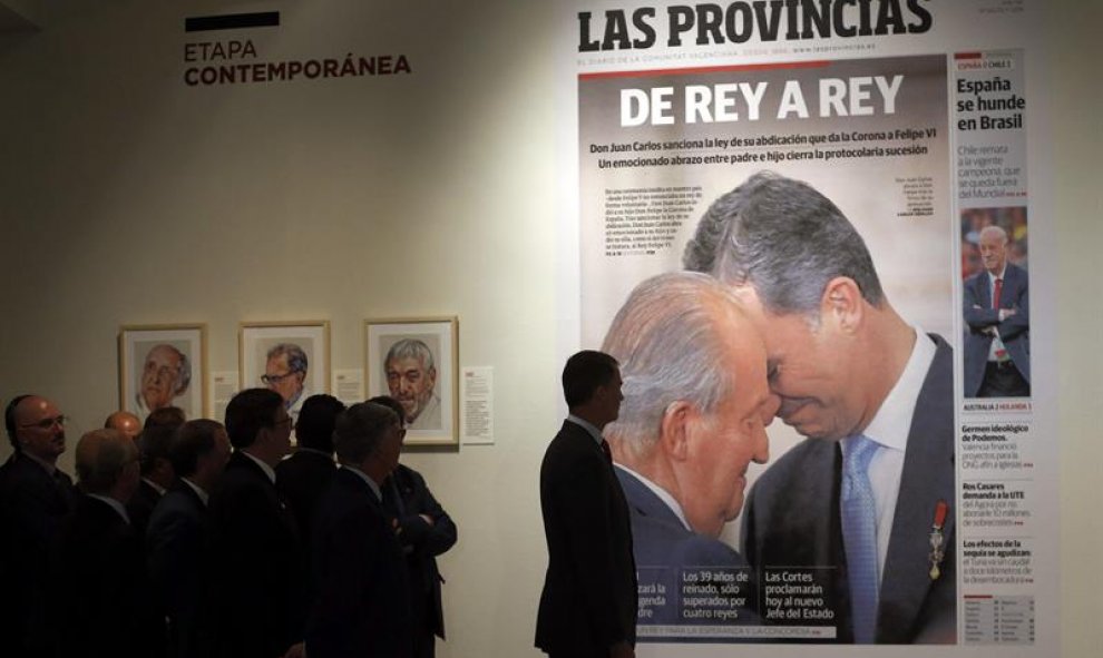 El rey Felipe VI contempla la portada dedicada a él y a su padre, Don Juan Carlos, en el acto protocolario de sucesión durante la inauguración hoy de la exposición "La huella de 150 valencianos en el 150º aniversario de Las Provincias" que ha presidido es