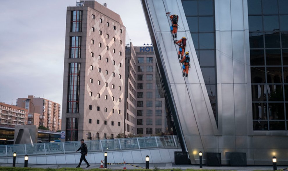 Un policía camina debajo de los activistas de Greenpeace al inicio de la escalada. GREENPEACE.