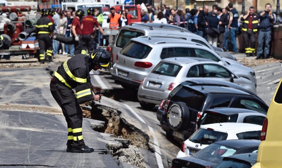 Un bombero trabaja en el rescate de varios vehículos engullidos por un socavón cerca del famoso Puente Viejo a orillas del río Arno, en el centro de la ciudad italiana de Florencia (Italia). EFE/Maurizio Degl' Innocenti