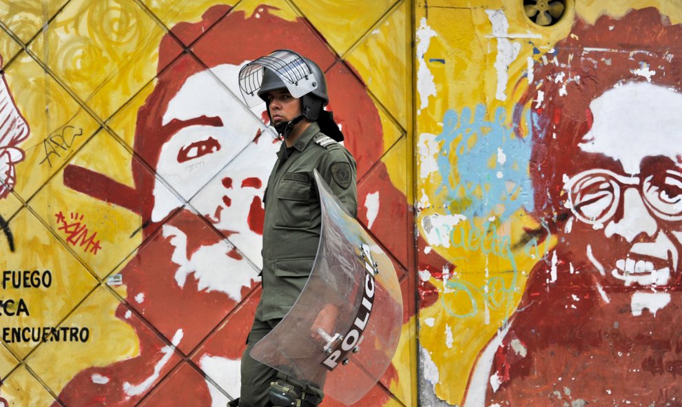 Un policía antidisturbios camina delante de una pared con un mural que representa a Ernesto 'Che' Guevara durante una manifestación de miles por la educación pública en Bogotá, Colombia. GUILLERMO LEGARIA / AFP