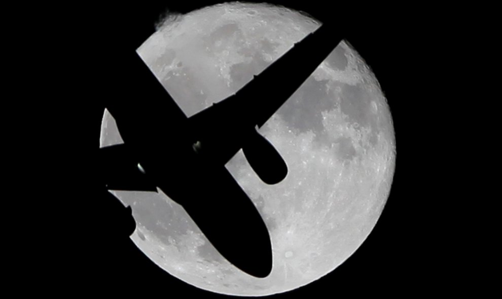 Un avión de pasajeros surca el cielo frente a la superluna en España. REUTERS/Jon Nazca