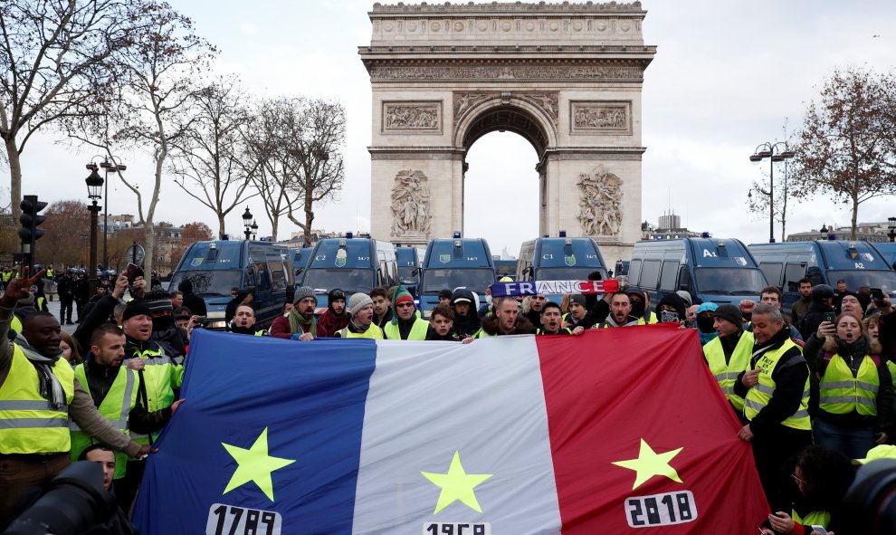 Manifestantes de los chalecos amarillos portan una bandera de Francia con tres fechas señaladas en cada franja: 1789, 1968 y 2018. REUTERS/Benoit Tessier