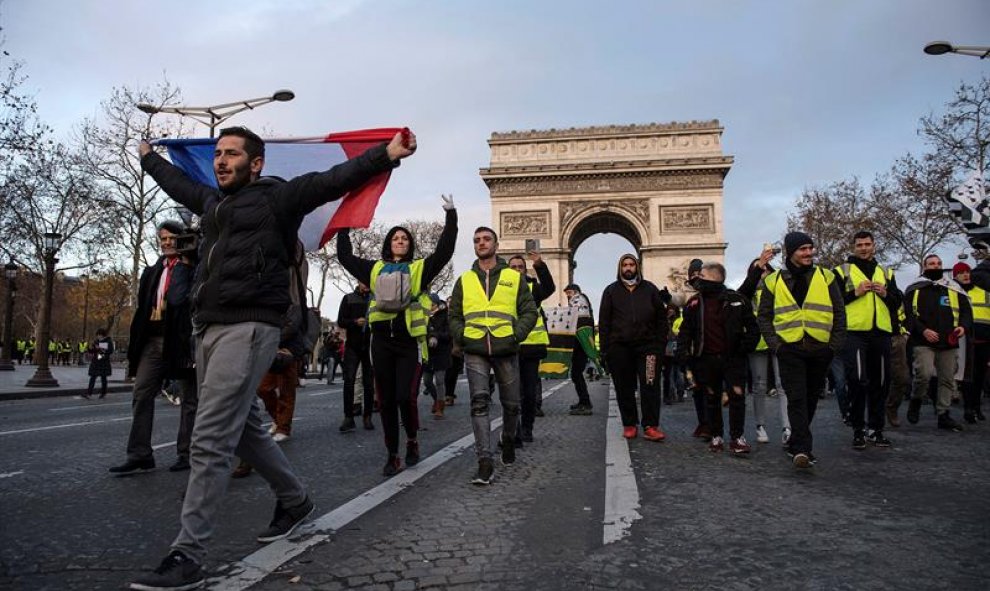 Manifestantes de los chalecos amarillos caminan por los Campos Elíseos de París./ EFE/EPA/Julien de Rosa