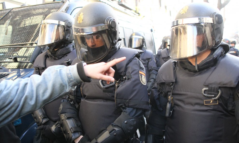 Una persona habla con unos agentes antidisturibios de la Policía Nacional en la inmediaciones de la calle Argumosa de Madrid. Eduardo Parra Europa Press