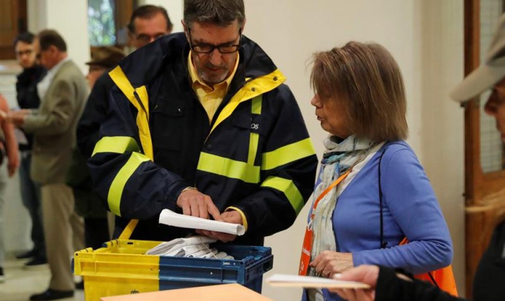 Un funcionario de correos hace entrega a la presidenta de una mesa del colegio electoral del Colegio Nuestra Señora del Pilar votos emitidos por correo. / EFE