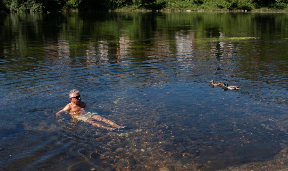 El sol y las altas temperaturas, entre 33 y 37 grados en la mayor parte de España, marcarán el inicio del mes de junio, con valores este viernes de 10 a 15 grados por encima de lo normal en el noroeste. En la imagen, un hombre se refresca en el río Miño.