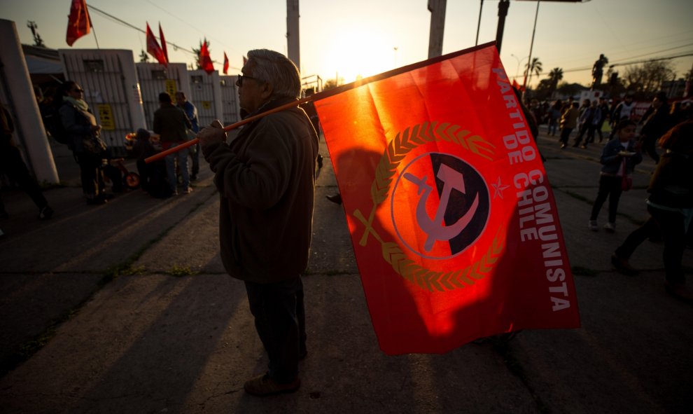 Un hombre con la bandera del Partido Comunista de Chile en las afueras del Estadio Nacional de Chile, uno de los centros de detención de la dictadura de Augusto Pinochet (1973-1990), durante uno de los actos de conmemoración por el 46º aniversario del gol