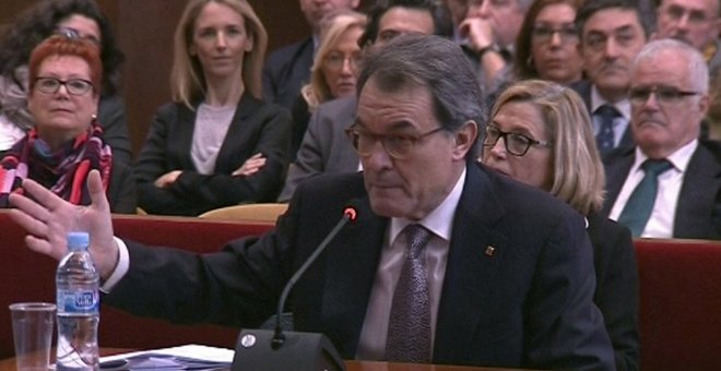 Imagen de televisión del expresidente de la Generalitat Artur Mas, durante su declaración en el juicio en el TSJC por la consulta del 9-N. A la derecha, con los brazos cruzados, entre el público, Cayetana Álvarez de Toledo, responsable del área de Interna